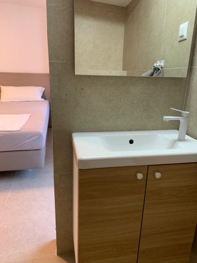 Bad 2 Badezimmer mit Waschbecken und Spiegel, im Hintergrund ein Schlafzimmer.