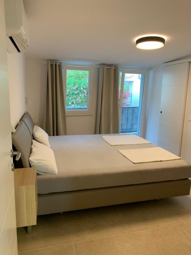 Schlafzimmer 1 Helles Schlafzimmer mit Doppelbett, Fenster und modernen Vorhängen.