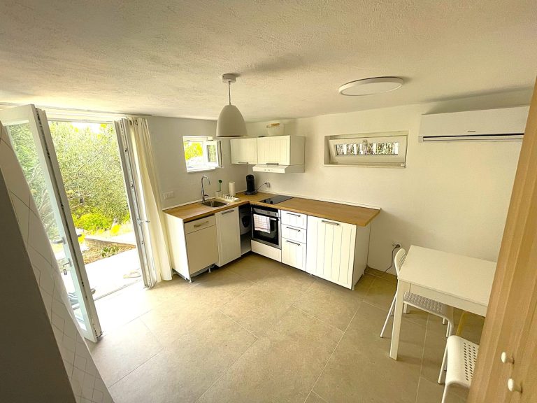 Küche/Essplatz Moderne Küche mit hellem Interieur, Holzarbeitsplatte und Zugang zum Außenbereich.