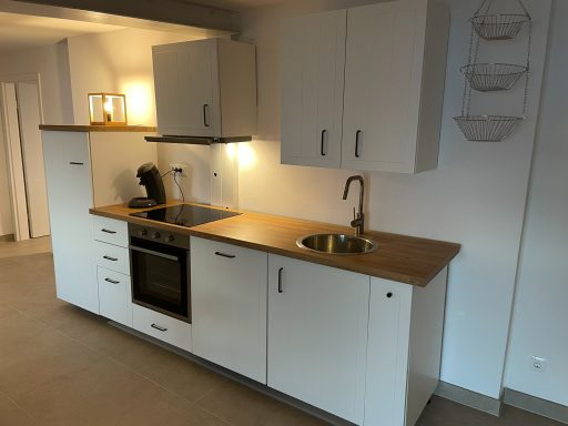 Küche Moderne Küche mit Holzarbeitsplatte, Spüle und Geräten. Helle Beleuchtung ergänzt das Design.