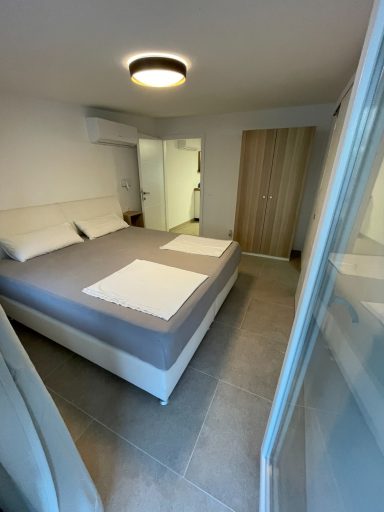 Schlafzimmer 2 Helles Schlafzimmer mit Doppelbett, grauer Bettwäsche und einem Holzschrank.