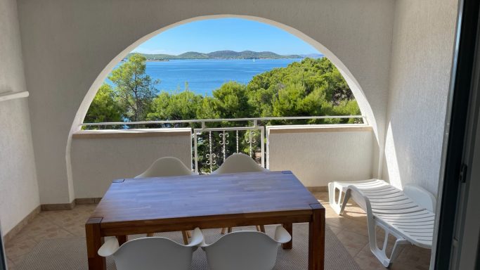 überdachte Terrasse mit wunderschönem Blick auf´s Meer Blick auf das Meer von einer Terrasse mit Tisch und Stühlen im Hintergrund.